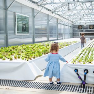 girl walking through plants in greenhouse
